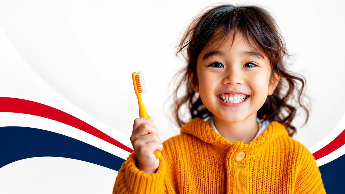 A smiling child holding a toothbrush at Brooklyn Dental Group